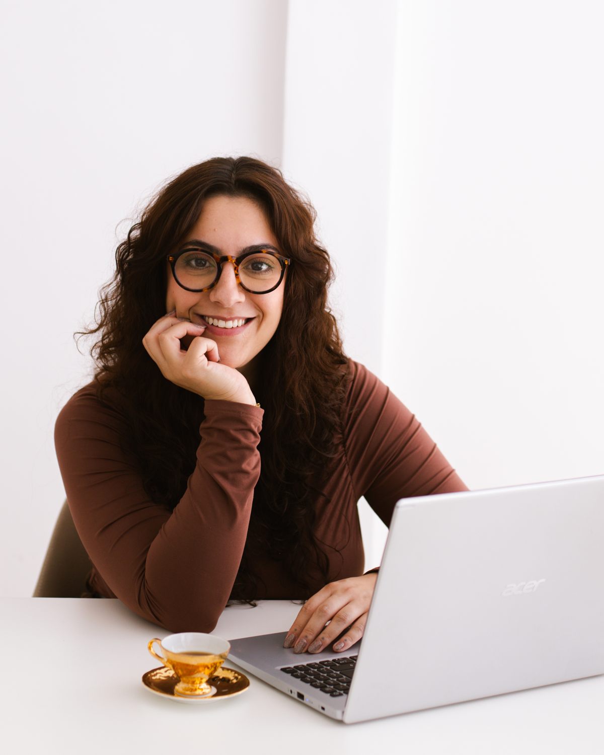 Ana Vitória, fundadora da Nimea, na mesa de trabalho com o notebook e uma xícara de café